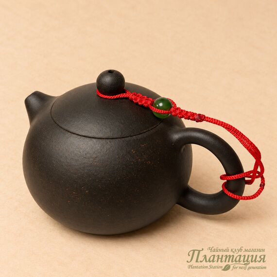 Шнурок для крышки чайника с зелёной бусиной; чайник показывает крепление